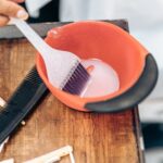 Zbliżenie na plastikową szczotkę w misce z farbą do włosów w salonie fryzjerskim