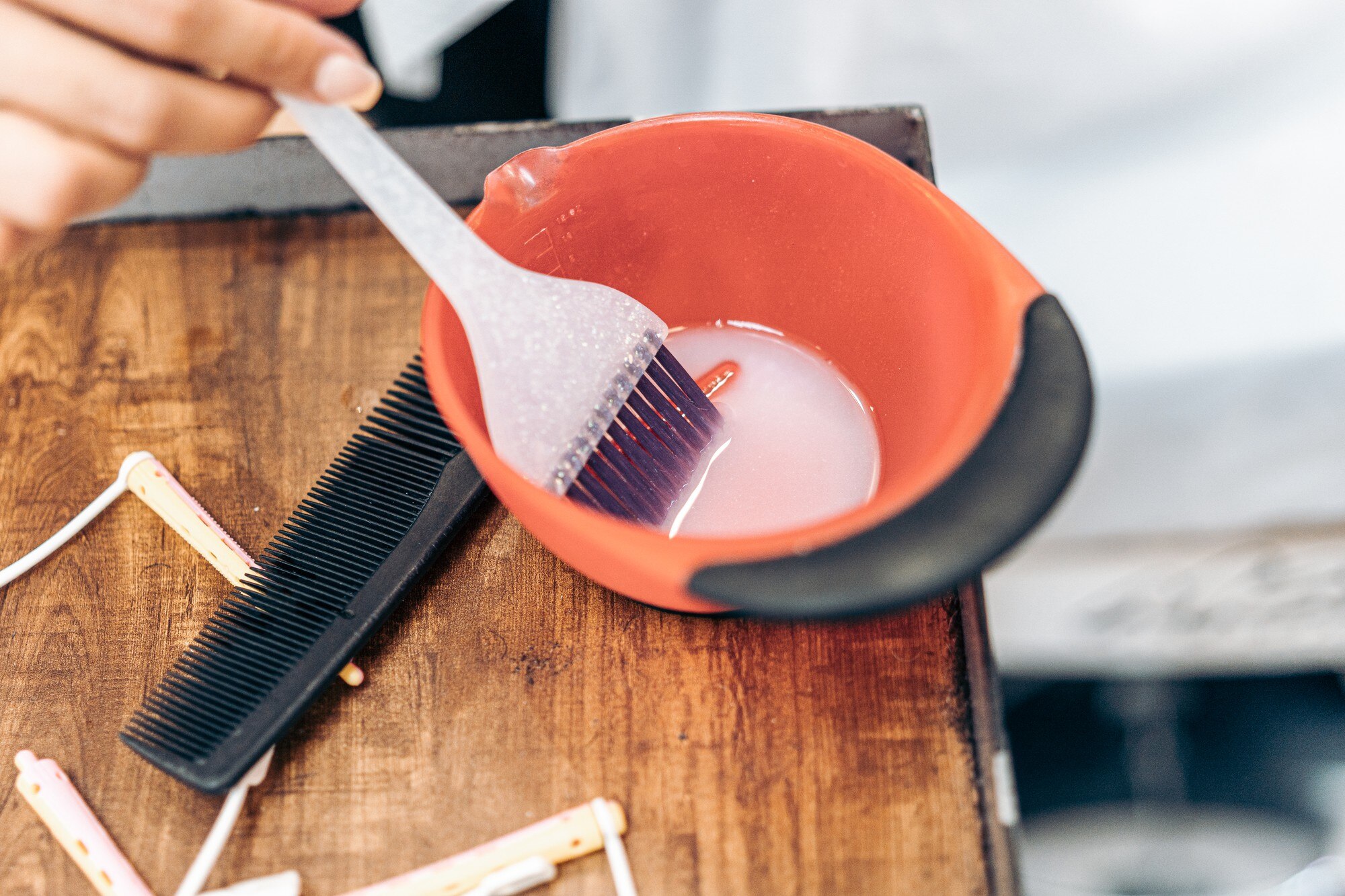 Zbliżenie na plastikową szczotkę w misce z farbą do włosów w salonie fryzjerskim