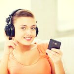 muzyka, internet i zakupy - kobieta ze słuchawkami i smartfonem w domu