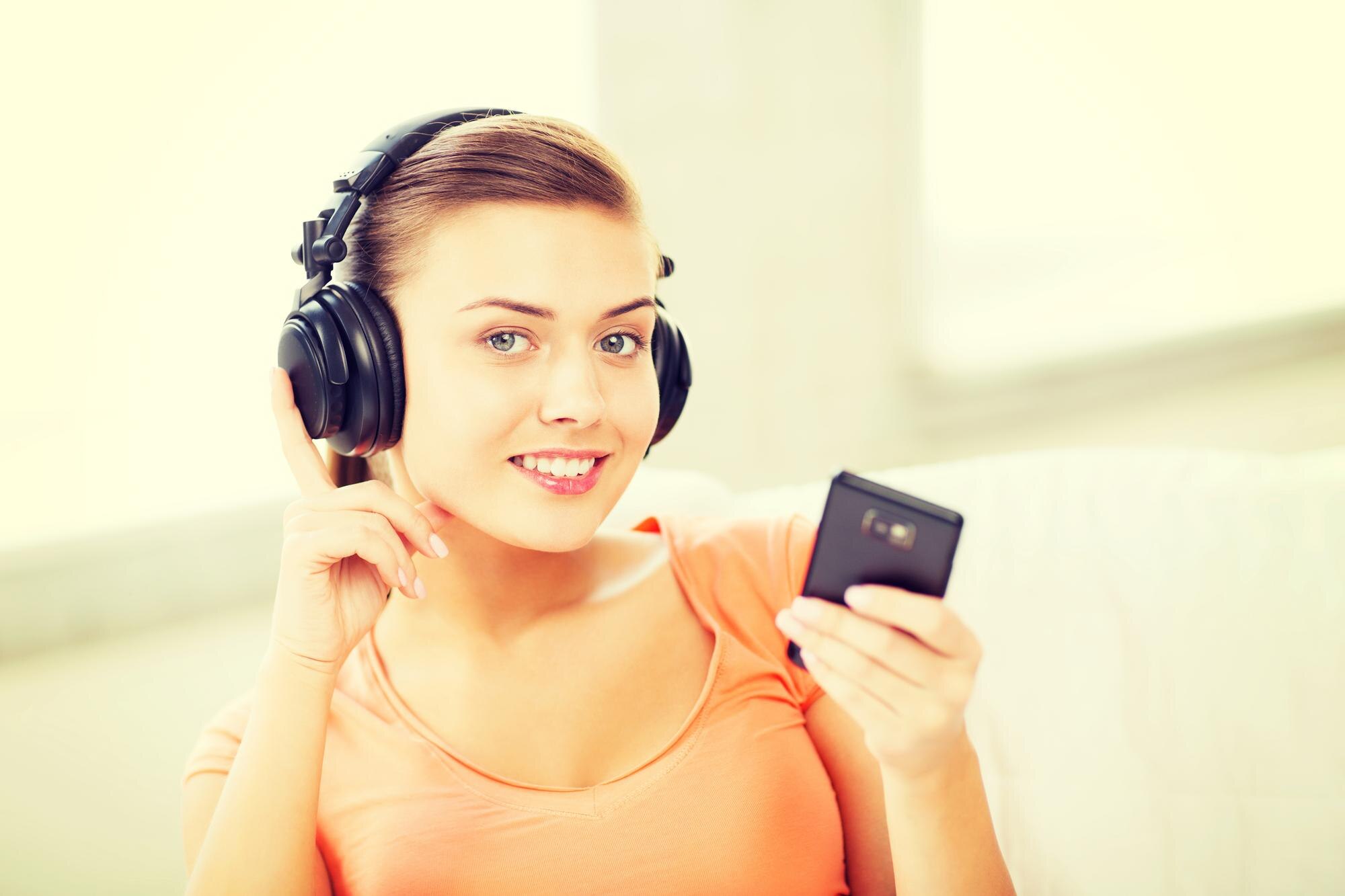 muzyka, internet i zakupy - kobieta ze słuchawkami i smartfonem w domu