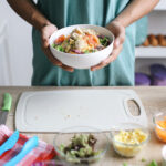 Mężczyzna z miską świeżych warzyw w kuchni