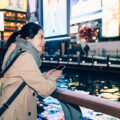 dziewczyna turysta stojący relaks nad rzeką w dotonbori osaka japonia. piękna pani podróżnik trzymając smartfon za pomocą SMS-ów online, widząc nocny widok na kanał i ruchliwe miasto.