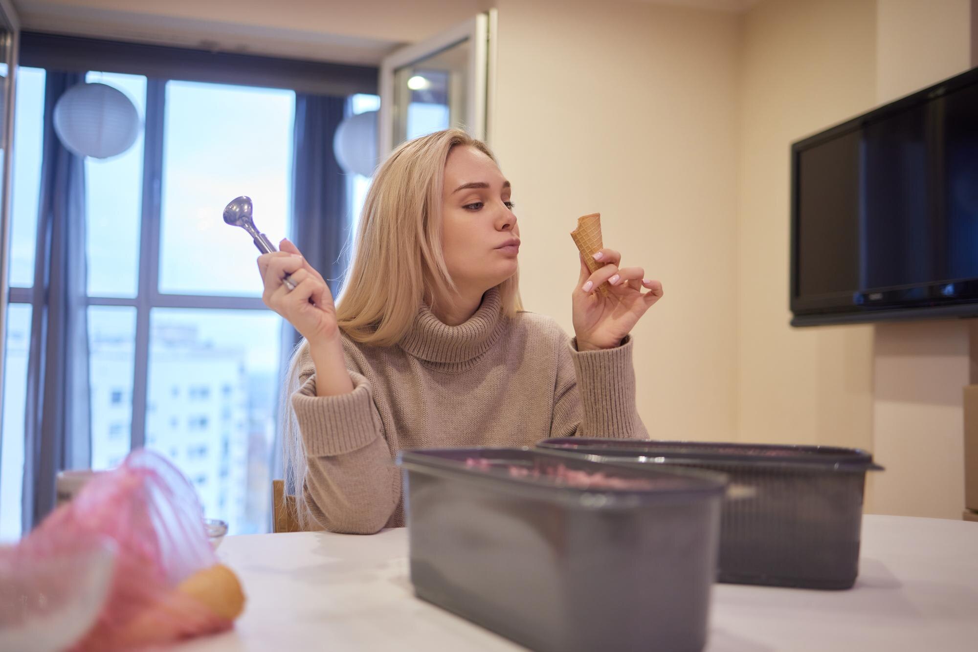 Uśmiechnięta dziewczyna jedząca lody ręce wkłada kulki lodów do rożka waflowego