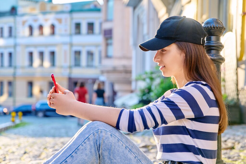 Styl miejski modne nastoletnie kobiety siedzące na chodniku za pomocą smartfona Moda wypoczynek styl życia lato uroda koncepcja młodzieży