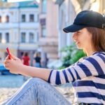 Styl miejski modne nastoletnie kobiety siedzące na chodniku za pomocą smartfona Moda wypoczynek styl życia lato uroda koncepcja młodzieży