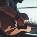 man playing acoustic guitar selective focus photography