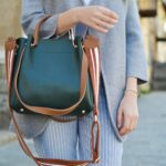 women standing while carrying green and brown leather 2-way shoulder bag